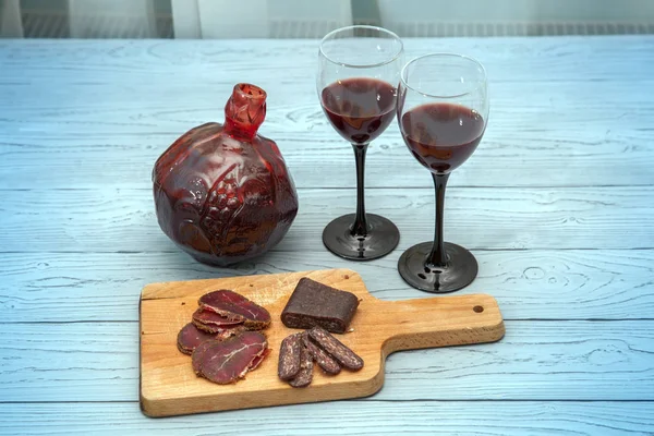 Pomegranate wine and meat appetizer on table.