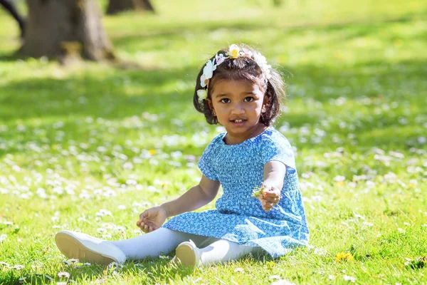 春の公園の緑の芝生の上に座っているアジアの女の子 — ストック写真