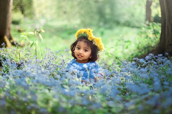 タンポポのリースを持つ小さな女の子が私を忘れないのフィールドに座っている青い花 — ストック写真