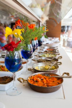 Vazolarda tropikal çiçekler olan açık büfe masası.