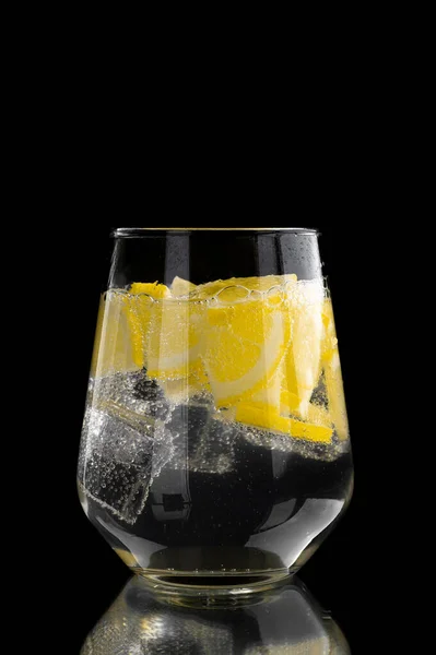 Soda water with lemon and ice in a glass on a black background — Stock Photo, Image