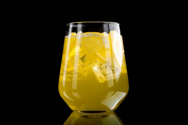 Освіжаючий лимонад зі скибочками лимона та кубиками льоду на чорному тлі — стокове фото