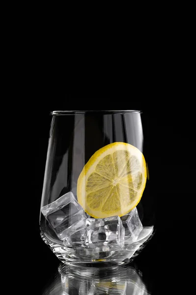 Стекло со льдом и лимоном без воды на черном фоне — стоковое фото