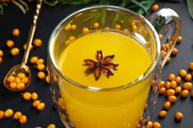 Siyah arka planda baharatlı kum dikenli çay.