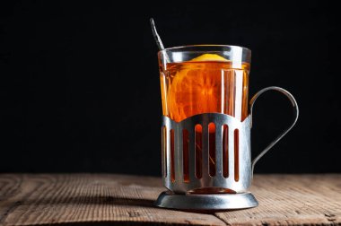  Bardakta limonlu çay, tahta arka planda bir bardak tutacağı ve siyah bir arka planı var.