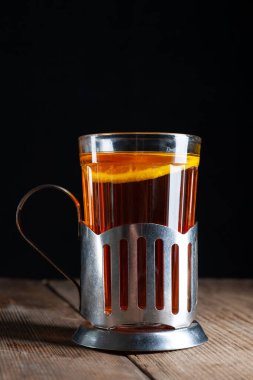  Bardakta limonlu çay, tahta arka planda bir bardak tutacağı ve siyah bir arka planı var.
