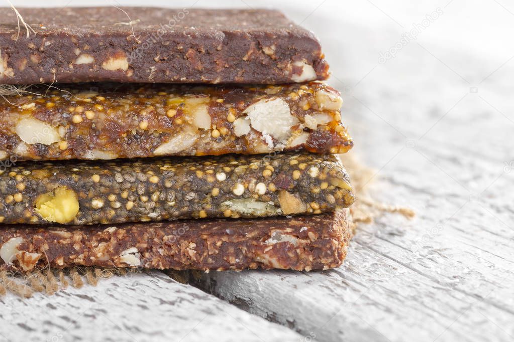 Close up of tasty raw bars from fruits and nuts on wooden background
