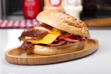 Burger kızarmış yumurta, peynir, sebze ve sosis ahşap tahta üzerinde Kapat