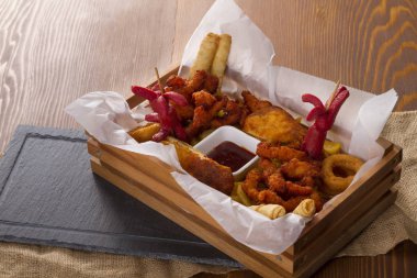 Lezzetli sıcak gevrek ev yapımı taze kızarmış tabak içinde tavuk kanatları, domuz sosisi, dilimlenmiş patates, soğan ve peynir Filo hamur rulo dolması