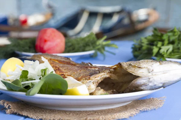 Yeşil ve mavi ahşap masa açık havada limon ile ızgara levrek balık