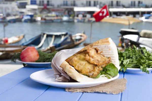 Mavi ahşap masada açık havada lezzetli kızarmış balık sandviç