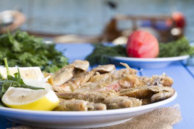 Yeşiller ve limon mavi ahşap tablo açık havada, deniz ürünleri ile kızarmış balık yakın çekim