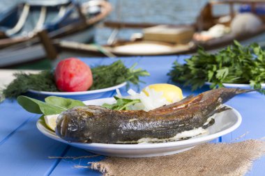 Yeşil ve mavi ahşap masa açık havada limon ile ızgara levrek balık