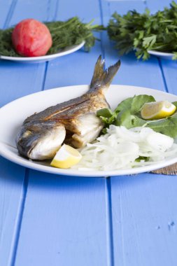 Yeşil ve mavi ahşap masa, deniz ürünleri kavramı üzerinde limon ile ızgara dorado balık