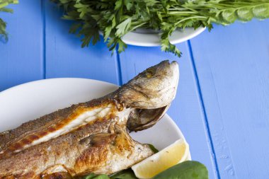 Yeşil ve mavi ahşap masa, deniz ürünleri kavramı üzerinde limon ile ızgara levrek balık