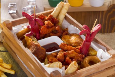 Lezzetli sıcak gevrek ev yapımı taze kızarmış tabak içinde tavuk kanatları, domuz sosisi, dilimlenmiş patates, soğan ve peynir Filo hamur rulo dolması