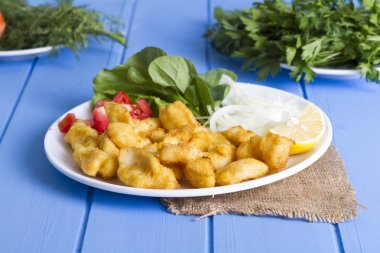 Kızarmış balık dilimleri ile yeşil ve mavi ahşap masa, deniz ürünleri üzerinde limon