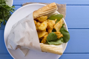 kızarmış balık dilimleri ve yeşillik ile lezzetli sandviç üstten görünüm mavi ahşap tablo 