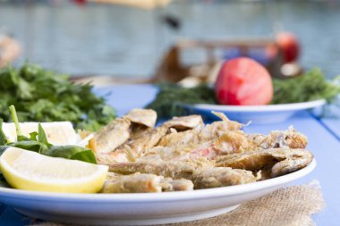 Yeşiller ve limon mavi ahşap tablo açık havada, deniz ürünleri ile kızarmış balık yakın çekim