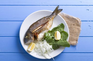 Yeşiller ve limon ile ızgara dorado balık üstten görünüm mavi ahşap masa, deniz ürünleri kavramı üzerinde