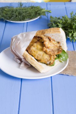 lezzetli kızarmış balık sandviç üzerinde mavi ahşap masa üzerinde Kapat 