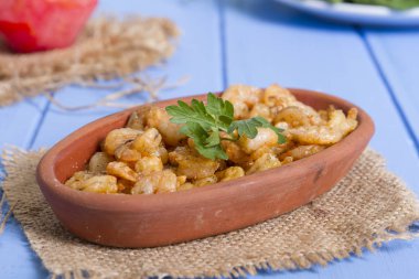 Lezzetli küçük kırmızı karides tereyağı ile baharat baharat haşlanmış. Geleneksel Yunan çanak çömlek içinde hizmet veren karides güveç. Üstten görünüm mavi rustik arka plan. En ortak gıda alerjenleri arasında diğer kabuklu deniz ürünleri.