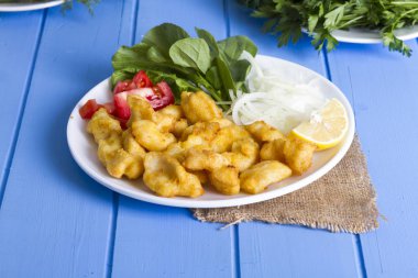 Kızarmış balık dilimleri ile yeşil ve mavi ahşap masa, deniz ürünleri üzerinde limon