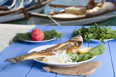 Yeşil ve mavi ahşap masa açık havada limon ile ızgara levrek balık