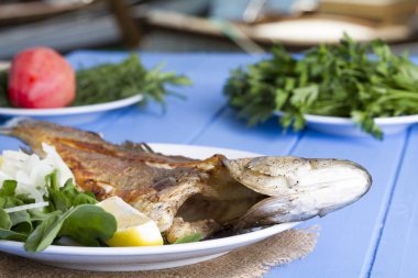 Yeşil ve mavi ahşap masa açık havada limon ile ızgara levrek balık