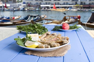 Yeşiller ve limon mavi ahşap tablo açık havada, deniz ürünleri ile kızarmış balık yakın çekim