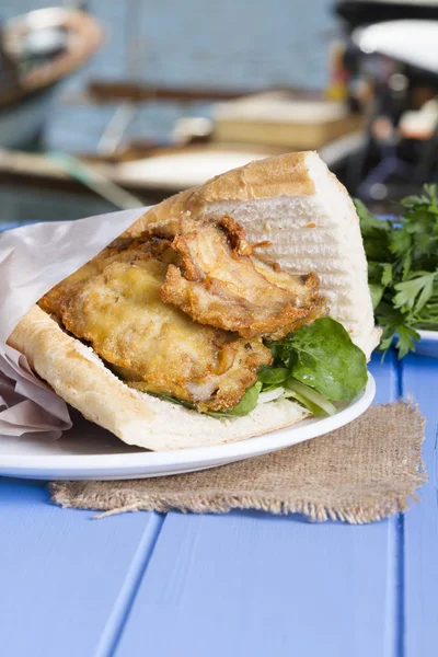 Mavi ahşap masada açık havada lezzetli kızarmış balık sandviç