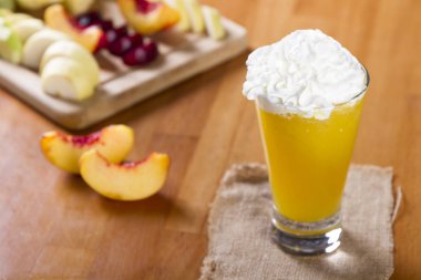 Bir kokteyl cam rustik ahşap zemin üzerine taze meyve ile lezzetli sağlıklı şeftali, portakal ve Mango smoothie. Güler yüzlü karışımlı ham meyve veya sebze yapılmış bir kalın içecektir