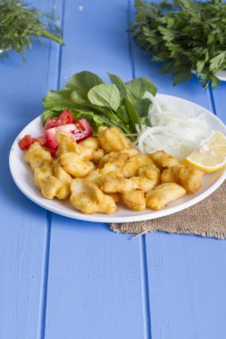 Kızarmış balık dilimleri yeşil ve mavi ahşap masa, deniz ürünleri üzerinde limon ile yakın çekim