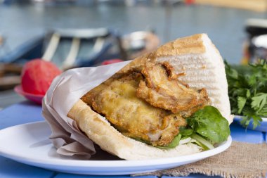 Mavi ahşap masada açık havada lezzetli kızarmış balık sandviç