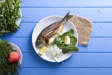 Yeşiller ve limon ile ızgara dorado balık üstten görünüm mavi ahşap masa, deniz ürünleri kavramı üzerinde