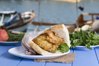 Mavi ahşap masada açık havada lezzetli kızarmış balık sandviç