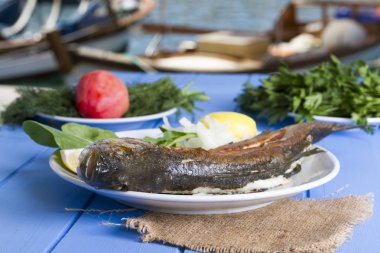 Yeşil ve mavi ahşap masa açık havada limon ile ızgara levrek balık