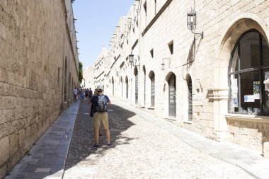 Rhodes, Yunanistan - 26 Ağustos 2017: turist Grand Master Şövalyeleri oldu hangi mimarisi inşa Knights döneminin şehrin altındaki XVI yüzyılda sokak yürüyüş. Kastello Ortaçağ kalesidir.