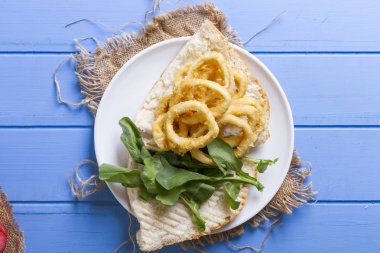 Lezzetli altın Ev yapımı Deep Fried tuzlu beyaz hizmet patates kızartması plaka rustik mavi ahşap masa arka plan üzerinde yuvarlak. Parmağı cipsi veya patates batonnet veya allumette derin kızarmış patates kesmek.