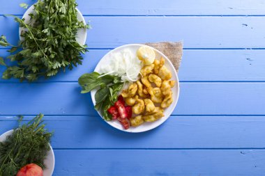 Kızarmış balık dilimleri ile yeşil ve mavi ahşap masa, deniz ürünleri üzerinde limon