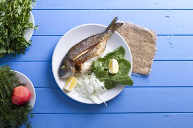 Yeşiller ve limon ile ızgara dorado balık üstten görünüm mavi ahşap masa, deniz ürünleri kavramı üzerinde