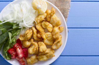 Kızarmış balık dilimleri ile yeşil ve mavi ahşap masa, deniz ürünleri üzerinde limon