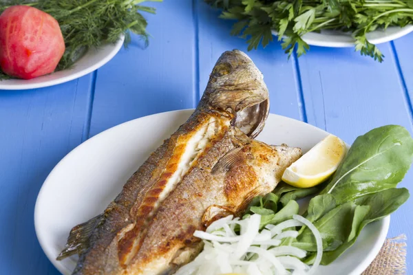 Yeşil ve mavi ahşap masa, deniz ürünleri kavramı üzerinde limon ile ızgara levrek balık