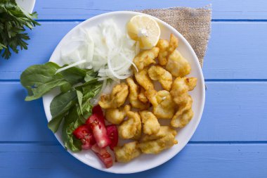 Kızarmış balık dilimleri ile yeşil ve mavi ahşap masa, deniz ürünleri üzerinde limon