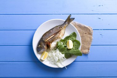 Yeşiller ve limon ile ızgara dorado balık üstten görünüm mavi ahşap masa, deniz ürünleri kavramı üzerinde