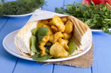 kızarmış balık dilimleri ve mavi ahşap masa üzerinde yeşillik ile lezzetli sandviç yakın çekim 