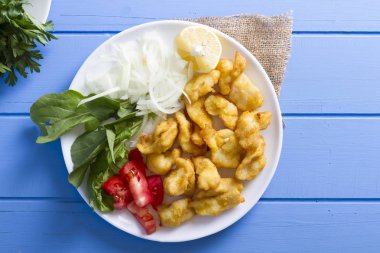 Kızarmış balık dilimleri ile yeşil ve mavi ahşap masa, deniz ürünleri üzerinde limon