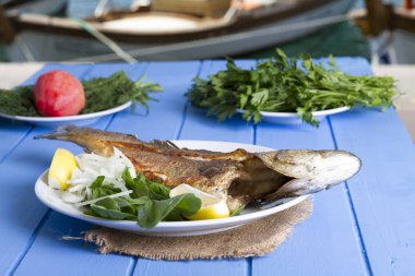 Yeşil ve mavi ahşap masa açık havada limon ile ızgara levrek balık