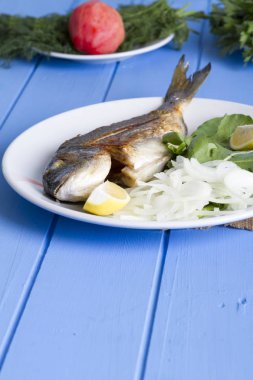 Yeşil ve mavi ahşap masa, deniz ürünleri kavramı üzerinde limon ile ızgara dorado balık