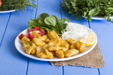 Kızarmış balık dilimleri ile yeşil ve mavi ahşap masa, deniz ürünleri üzerinde limon